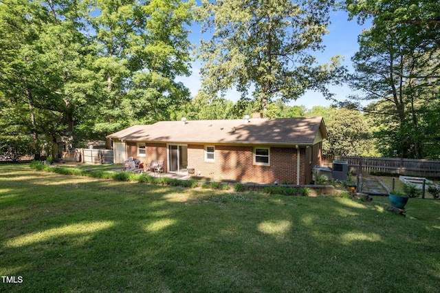 rear view of property with fence, brick siding, a chimney, a patio, and a yard