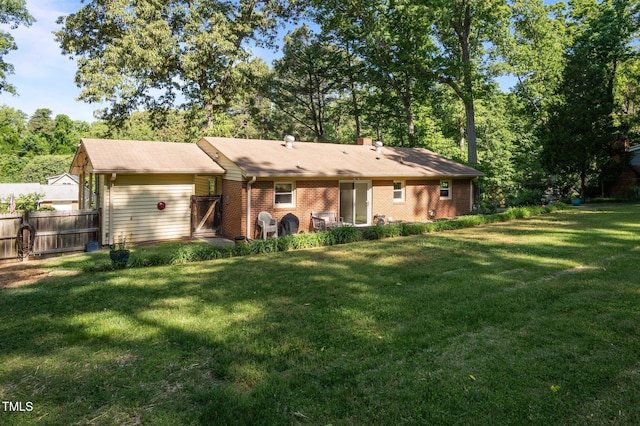 rear view of property featuring a yard, brick siding, and fence