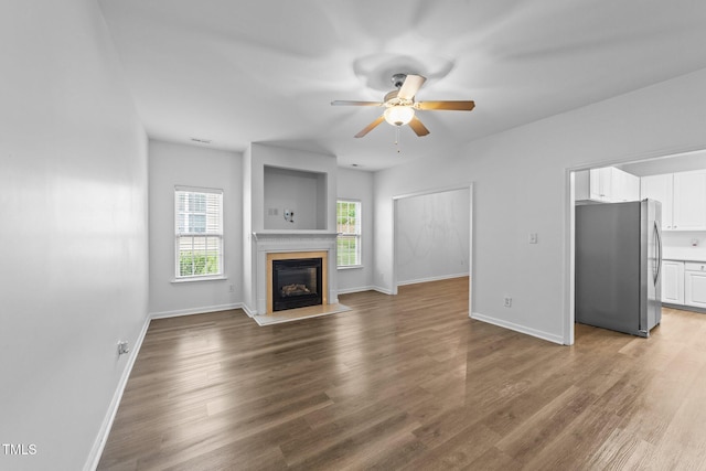 633 Prickly Pear Dr, Fuquay Varina, NC 27526 - unfurnished living room with ceiling fan, a glass covered fireplace, wood finished floors, and baseboards