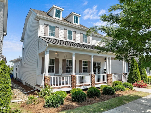 view of front of house with metal roof, covered porch, brick siding, and a standing seam roof