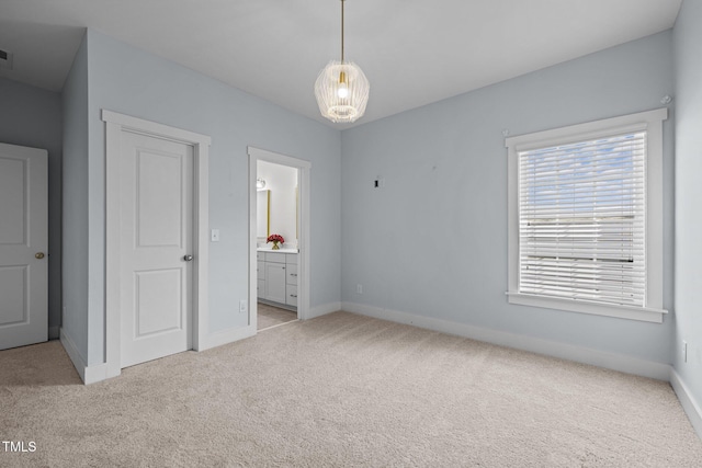 unfurnished bedroom with baseboards, light carpet, and connected bathroom
