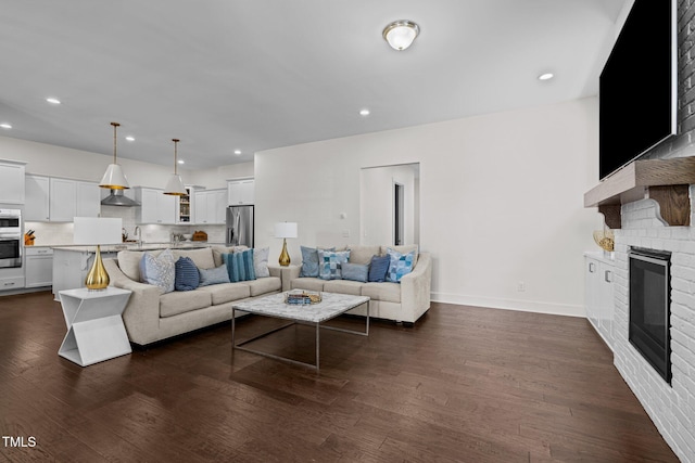 living area with recessed lighting, baseboards, a glass covered fireplace, and dark wood finished floors