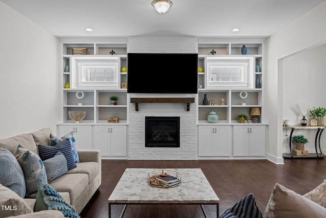 living room with built in features, a brick fireplace, and dark wood-type flooring