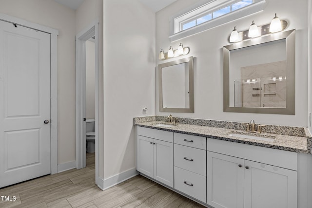 bathroom with double vanity, a walk in shower, toilet, and a sink