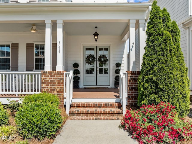 property entrance with french doors, a ceiling fan, a porch, and brick siding