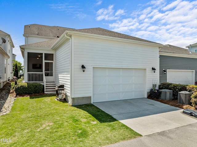 view of front of home featuring central AC unit, a sunroom, a front lawn, concrete driveway, and an attached garage