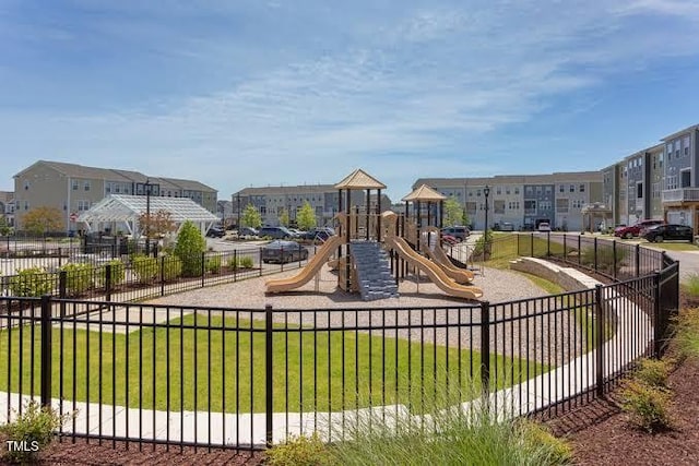 community play area featuring fence, a yard, and a residential view