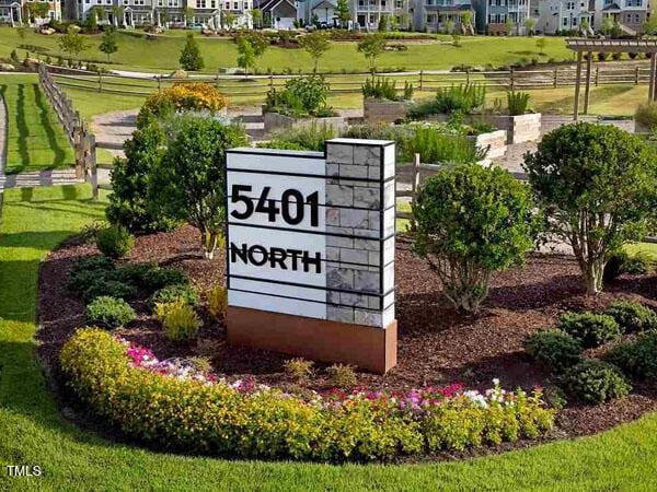 community sign with a lawn, fence, and a residential view