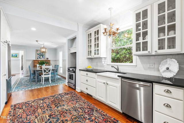 kitchen with a chandelier, stainless steel appliances, a sink, dark countertops, and crown molding