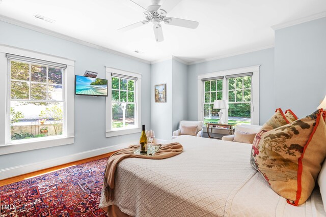 bedroom with wood finished floors, crown molding, baseboards, and a ceiling fan