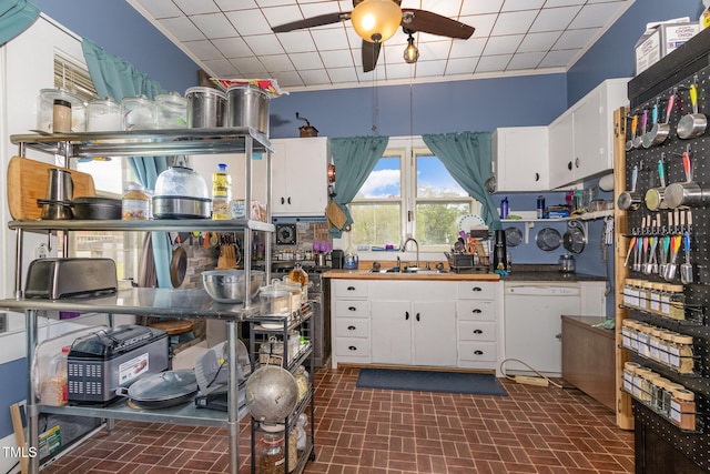 303 Wilcox St, Warrenton, NC 27589 - kitchen featuring dishwasher, a ceiling fan, brick patterned flooring, and white cabinets