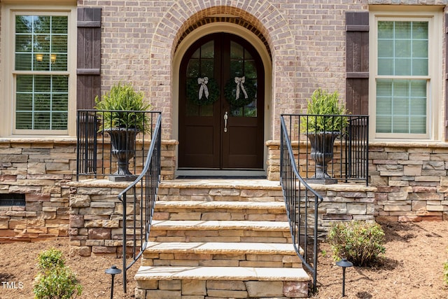 entrance to property featuring french doors and brick siding