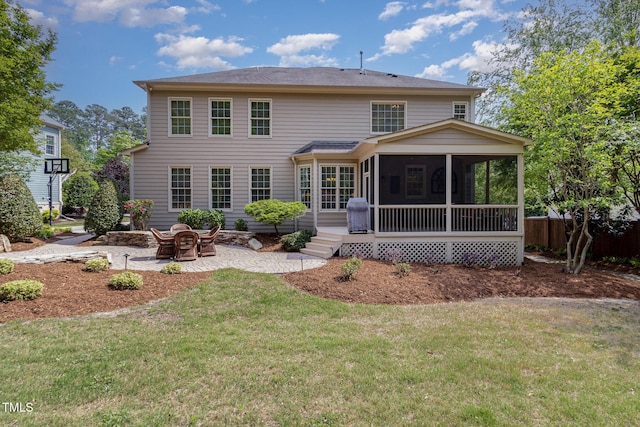 back of property with a sunroom, a patio area, and a yard