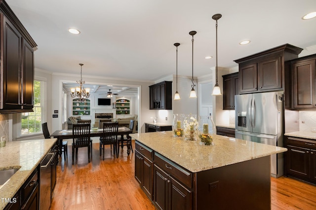 kitchen featuring dark brown cabinets, appliances with stainless steel finishes, ceiling fan with notable chandelier, tasteful backsplash, and ornamental molding