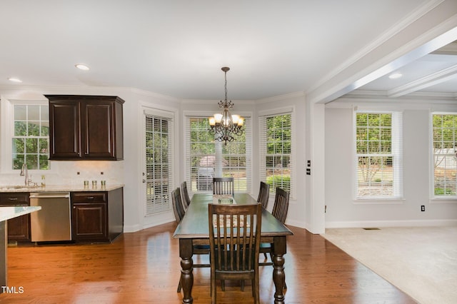dining space featuring baseboards, an inviting chandelier, ornamental molding, and a wealth of natural light