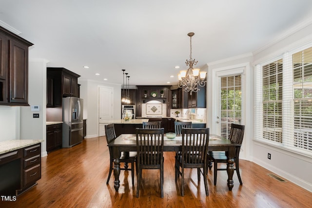 dining room with visible vents, crown molding, dark wood-style flooring, baseboards, and a chandelier