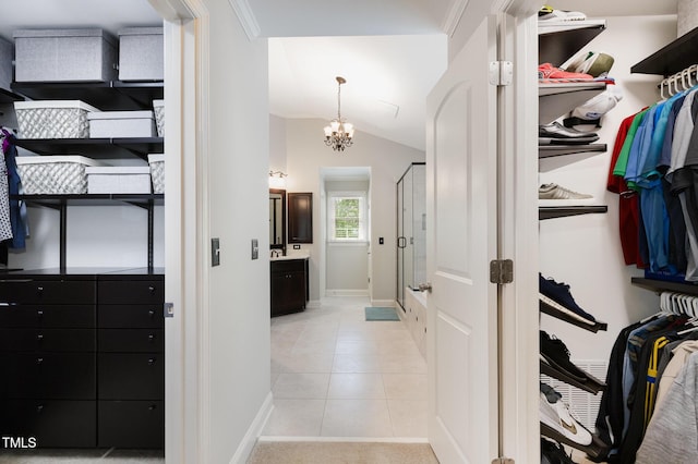 walk in closet with an inviting chandelier, light tile patterned floors, and vaulted ceiling