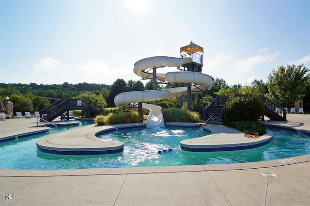 community pool featuring a water slide and stairway