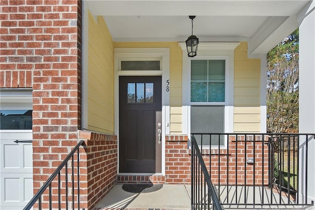 entrance to property featuring a porch and brick siding