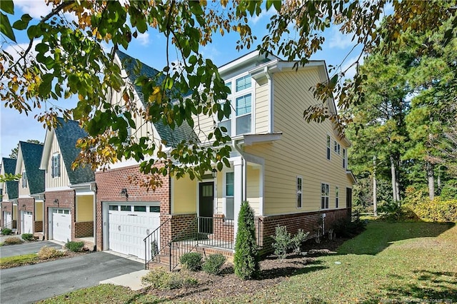 view of front of house with driveway, a front yard, brick siding, and an attached garage