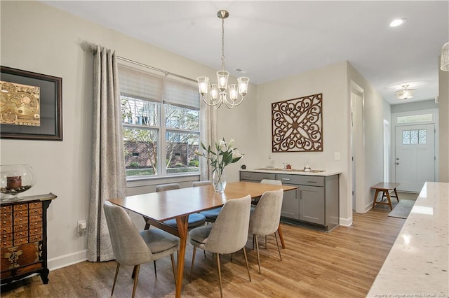 dining space with baseboards, recessed lighting, a notable chandelier, and light wood-style flooring