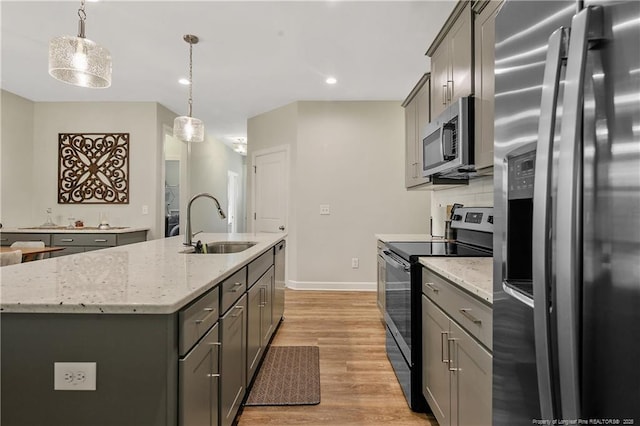 kitchen featuring appliances with stainless steel finishes, light wood-style flooring, gray cabinets, and a sink