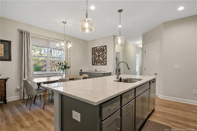 kitchen with stainless steel dishwasher, a sink, gray cabinetry, baseboards, and light wood finished floors