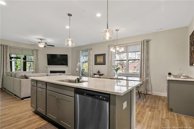 kitchen featuring light stone counters, light wood-style flooring, a sink, dishwasher, and gray cabinets