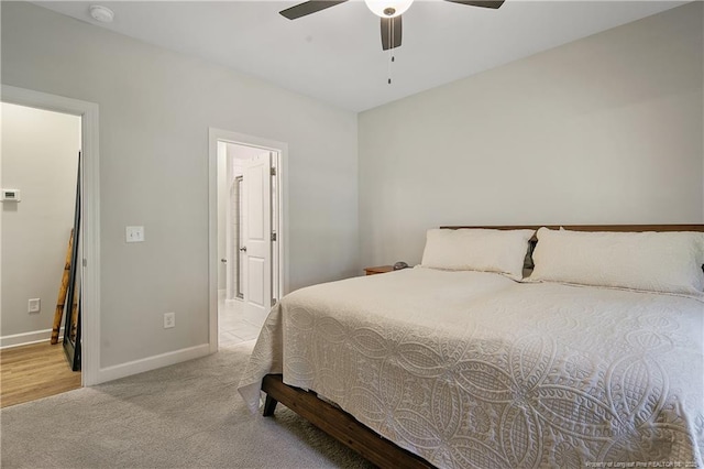 bedroom with a ceiling fan, ensuite bath, carpet floors, and baseboards