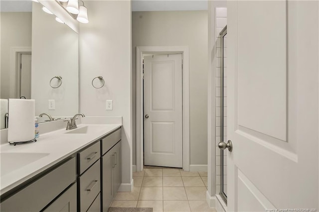 bathroom with double vanity, a sink, tile patterned floors, and baseboards