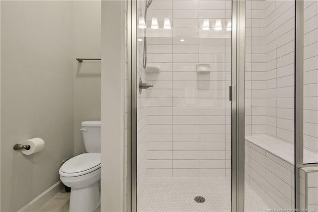 full bath featuring toilet, tile patterned flooring, a stall shower, and baseboards