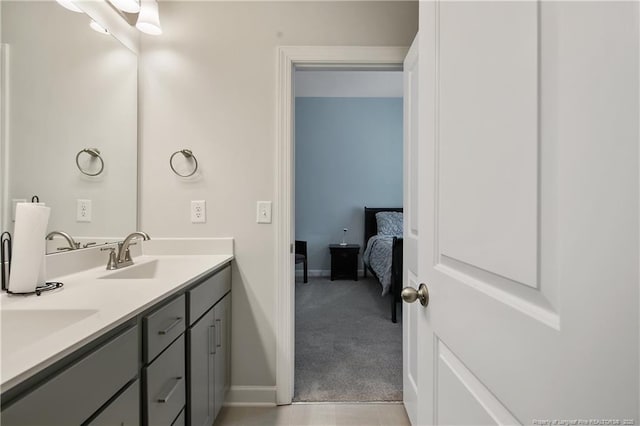 bathroom with baseboards, double vanity, and a sink