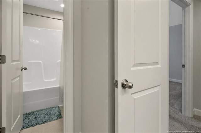 bathroom with bathtub / shower combination and baseboards