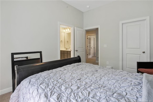 bedroom with connected bathroom, a sink, carpet, and baseboards