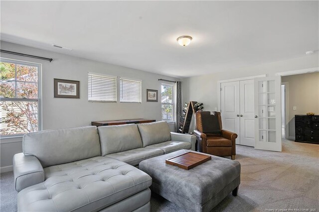 living room featuring visible vents, french doors, and light colored carpet