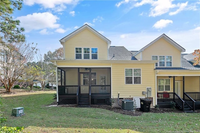 rear view of property featuring a sunroom, ceiling fan, cooling unit, a lawn, and roof with shingles