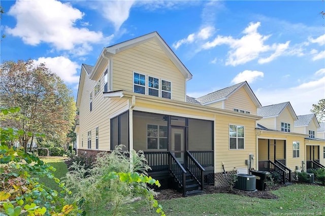 back of property featuring a lawn, a ceiling fan, central air condition unit, and a sunroom
