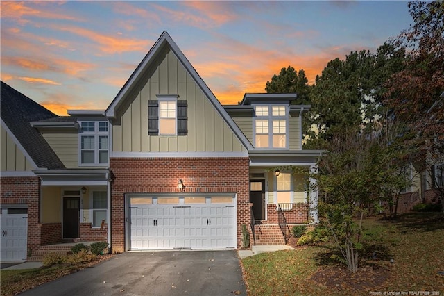 view of front facade featuring covered porch, driveway, board and batten siding, brick siding, and an attached garage