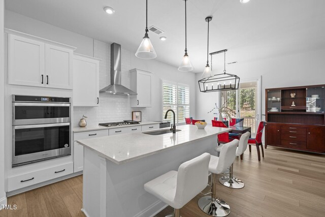 386 The Parks Dr, Pittsboro, NC 27312 - kitchen featuring a sink, wall chimney range hood, appliances with stainless steel finishes, tasteful backsplash, and white cabinetry