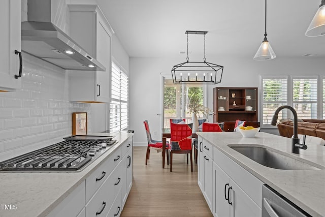 386 The Parks Dr, Pittsboro, NC 27312 - kitchen with wall chimney exhaust hood, stainless steel appliances, a sink, light wood-type flooring, and backsplash