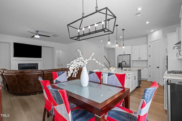 386 The Parks Dr, Pittsboro, NC 27312 - dining space with light wood-style floors, recessed lighting, ceiling fan, wine cooler, and a fireplace