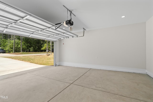garage featuring baseboards, a garage door opener, and recessed lighting