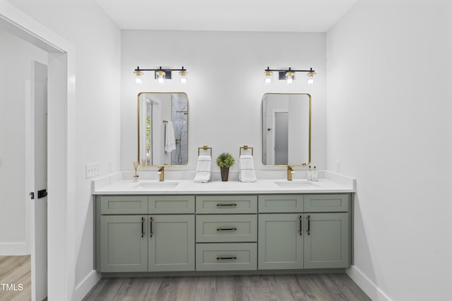 bathroom featuring double vanity, a sink, baseboards, and wood finished floors