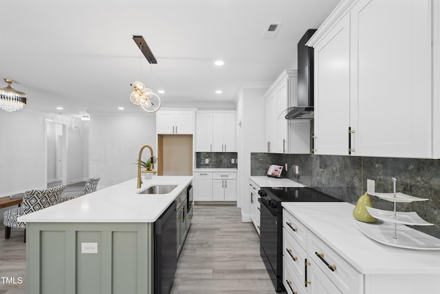 kitchen with wall chimney range hood, black electric range, dishwasher, a sink, and white cabinetry