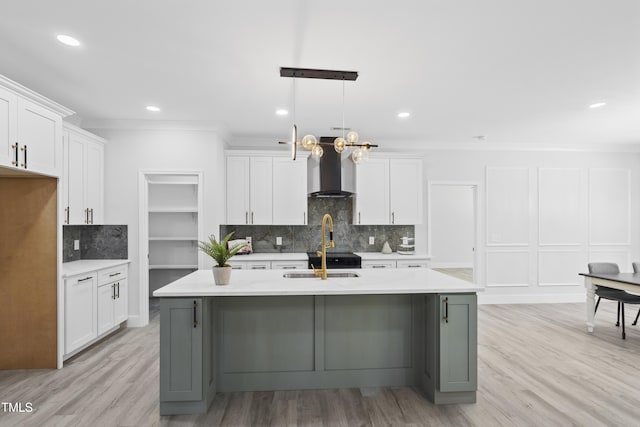 kitchen with wall chimney range hood, decorative backsplash, a sink, light countertops, and ornamental molding