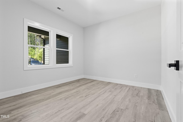 empty room featuring baseboards, wood finished floors, and visible vents