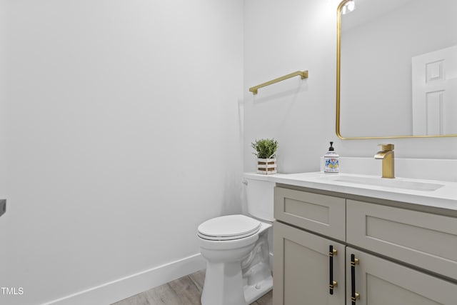 bathroom with vanity, baseboards, toilet, and wood finished floors