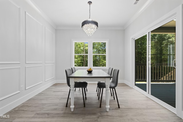 dining area featuring an inviting chandelier, baseboards, crown molding, and light wood finished floors