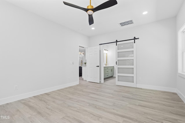 unfurnished bedroom with visible vents, baseboards, recessed lighting, a barn door, and light wood-style flooring