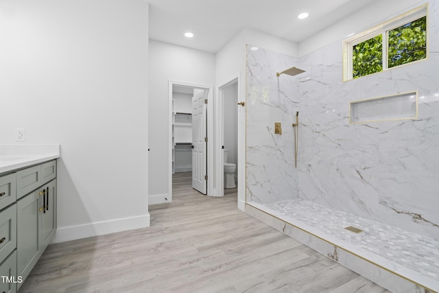 full bath featuring wood finished floors, vanity, toilet, a marble finish shower, and recessed lighting